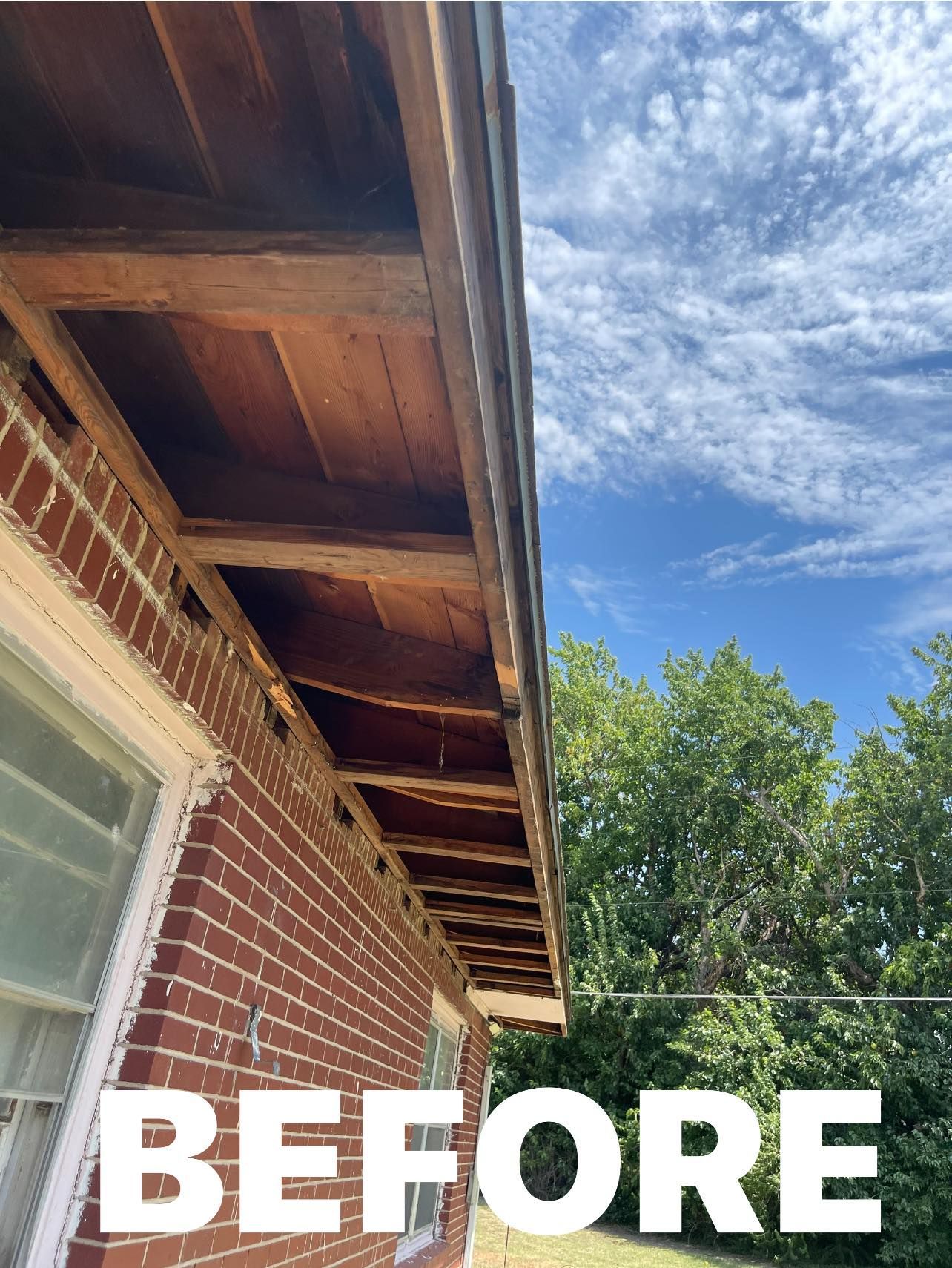 A before picture of a wooden roof on a brick house.