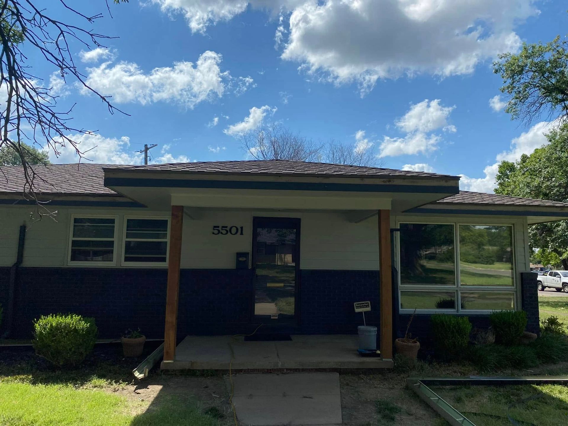A black and white house with a porch and a blue sky in the background.