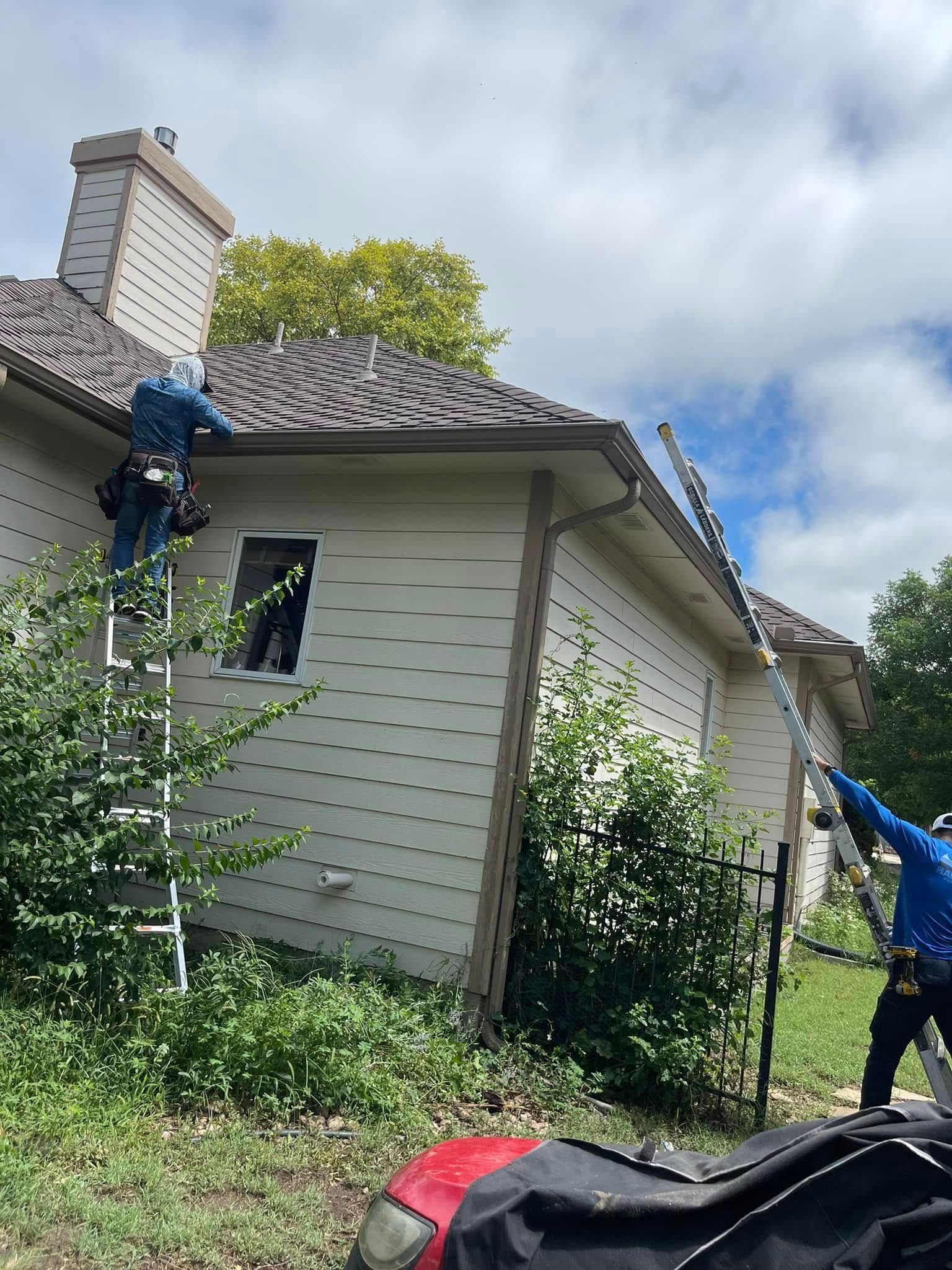 A man is standing on a ladder on the side of a house.