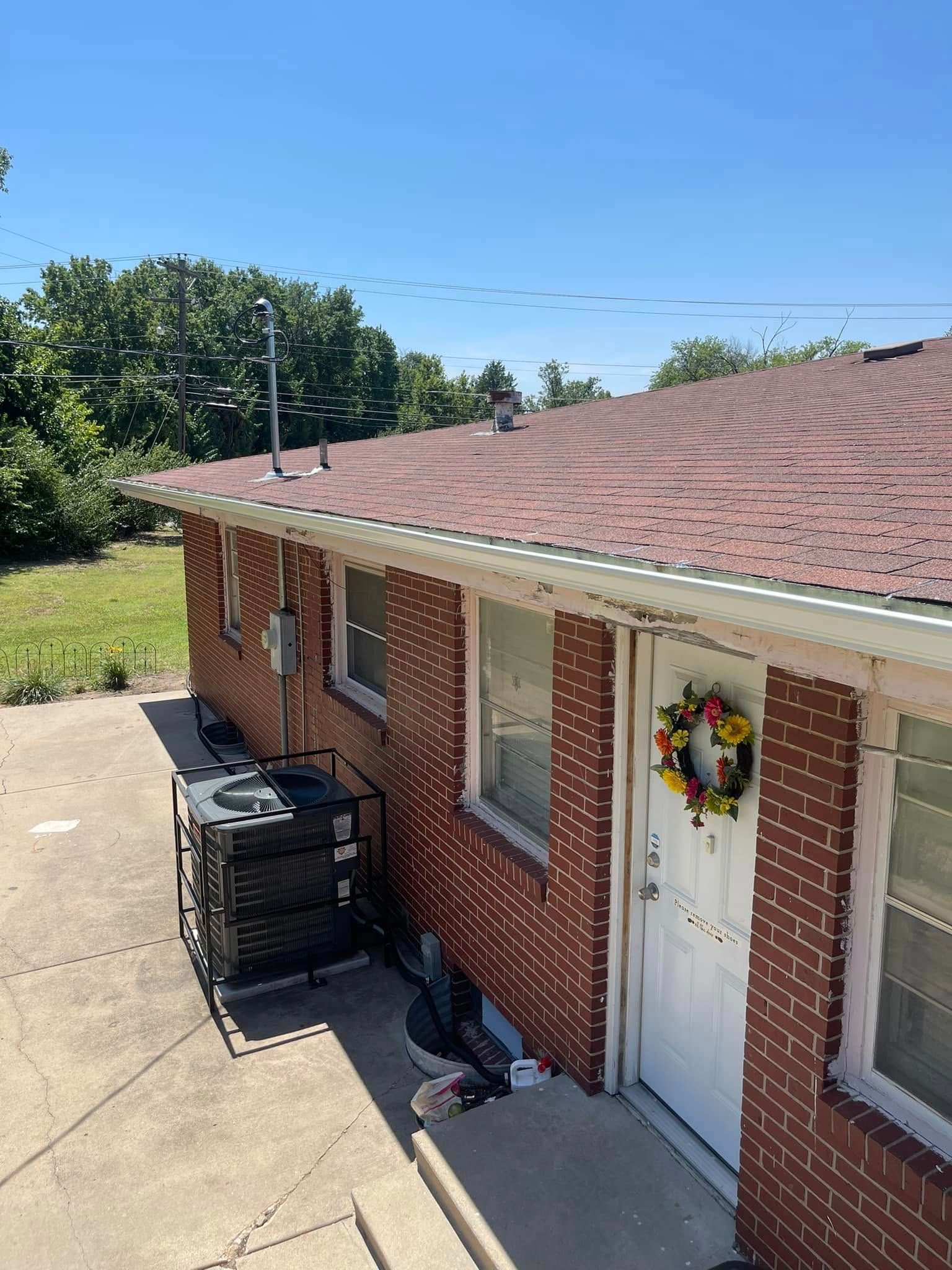 A brick house with a red roof and a wreath on the door.