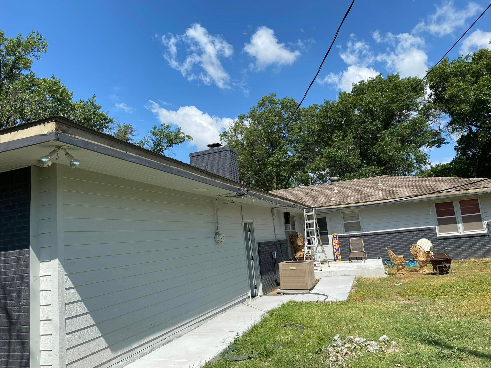 A white house with a roof that is being remodeled.