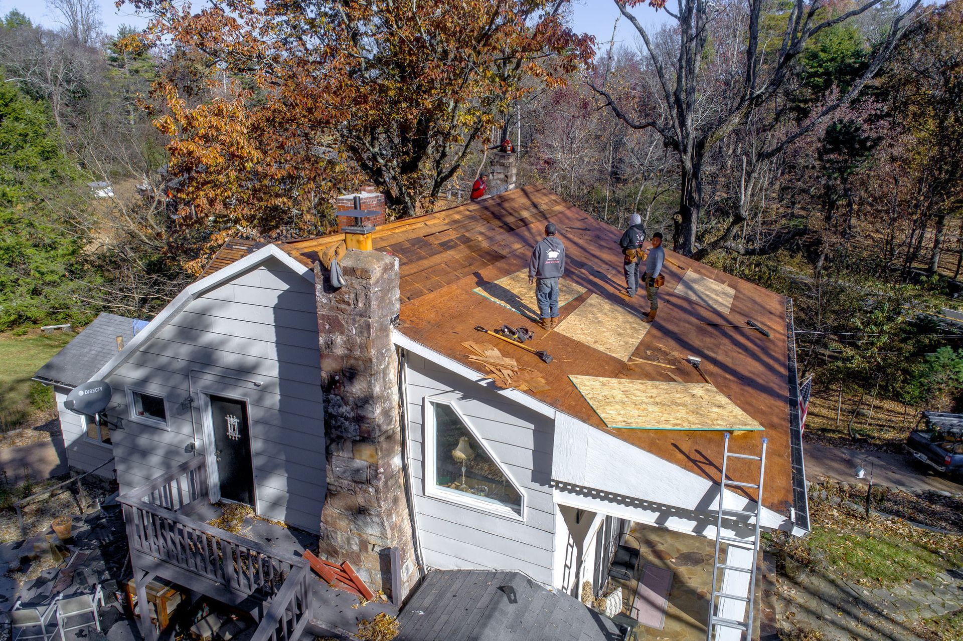 A group of people are working on the roof of a house.