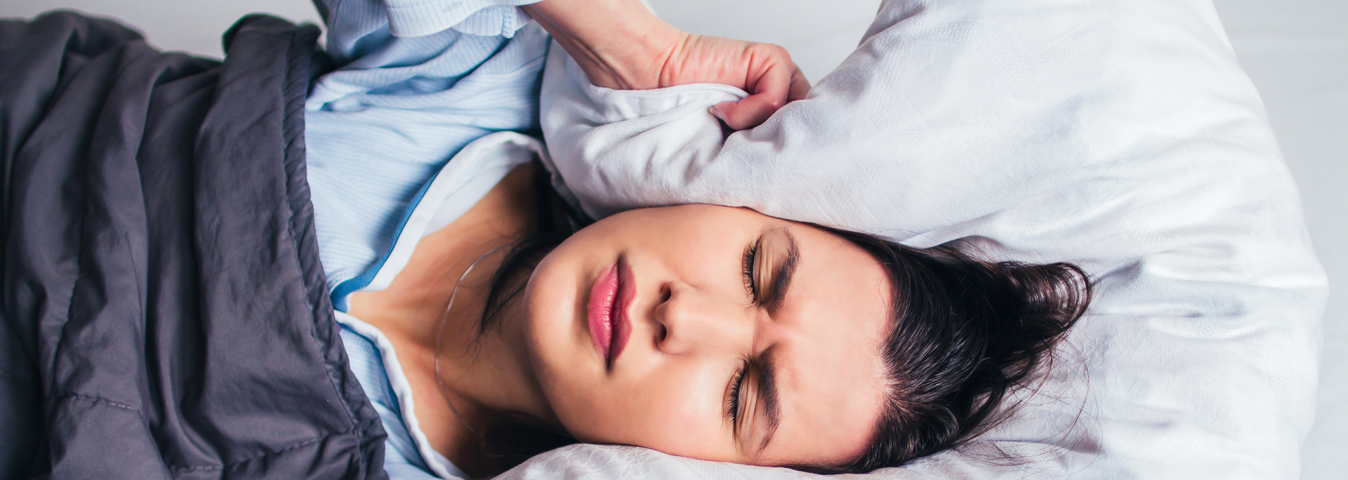 Picture of someone covering their ears, struggling to sleep