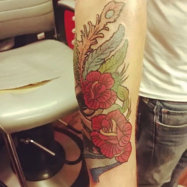 tatuering av Jonas Finnze på en mans arm, föreställande stiliserade rosor