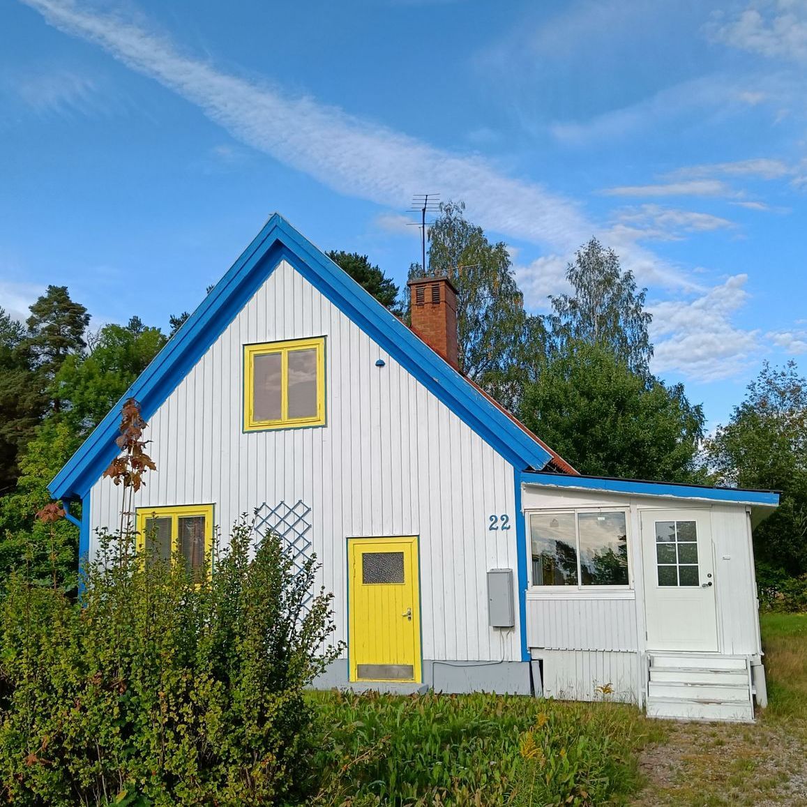Hus med himmelsblå vindskivor, gula fönster och gul dörr. Fasaden är vit.