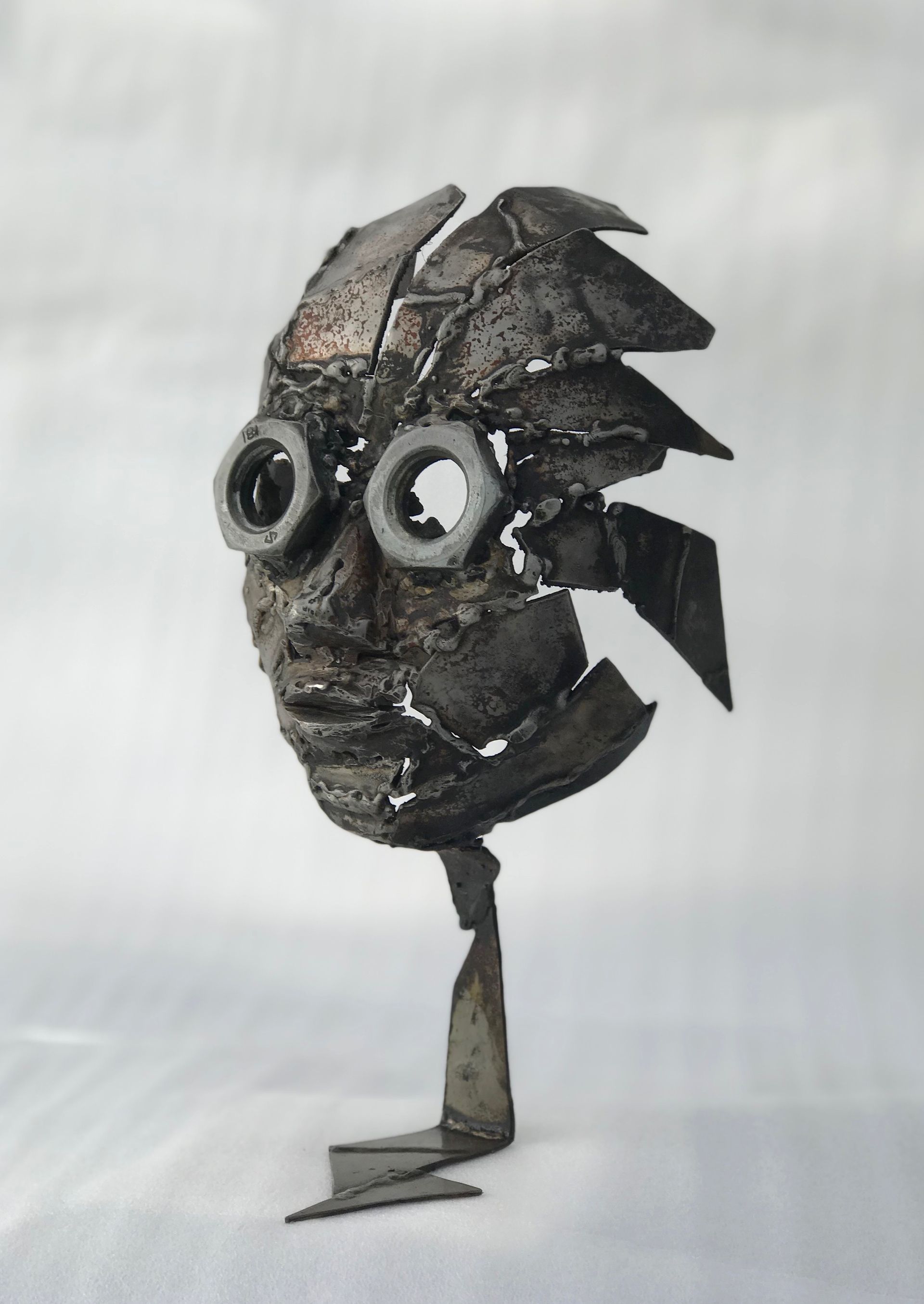 Skulptur av Olav Lunde i form av ett ansikte, tillverkad av ihopsvetsade metalldelar. Ögonen är gjorda av stora muttrar.