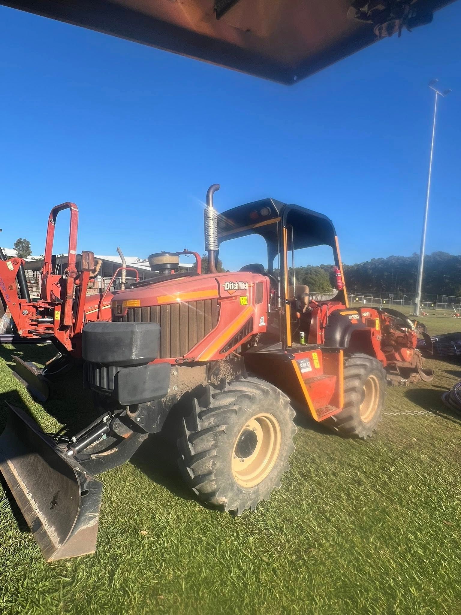 Red Tractor With a Front-end Loader on Grass, Sunny Day — North Coast Heavy Diesel In Taree, NSW