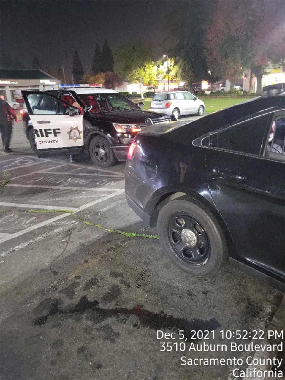 A police car is parked in a parking lot next to a black car.