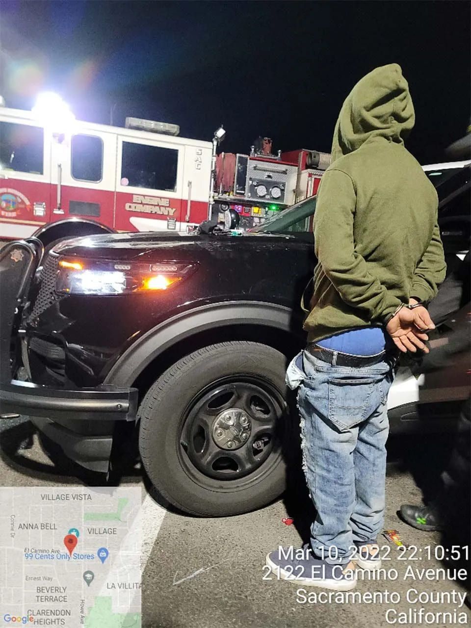 A man in a green hoodie is standing next to a black truck.