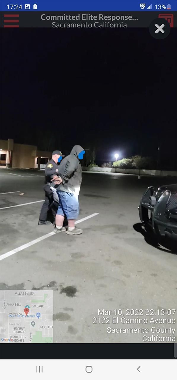 A man is being led by a security guard to a car.