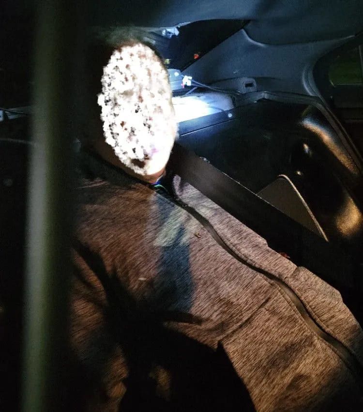 A person is sitting in the driver 's seat of a car at night.