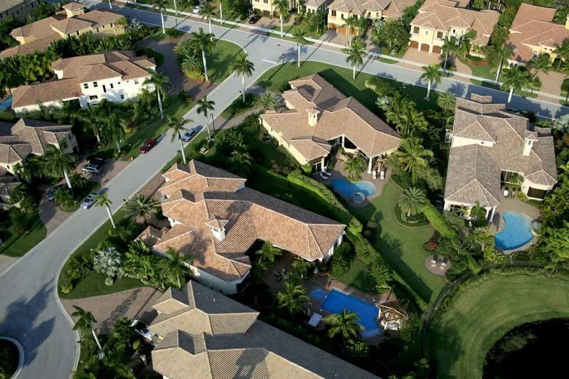An aerial view of a residential area with lots of houses and palm trees