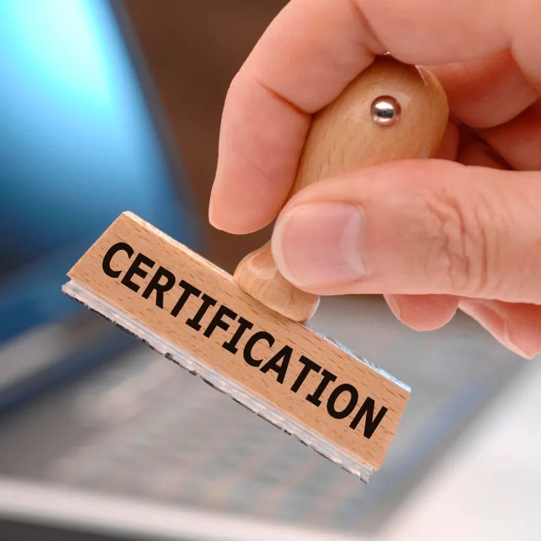 A person is holding a wooden stamp that says certification