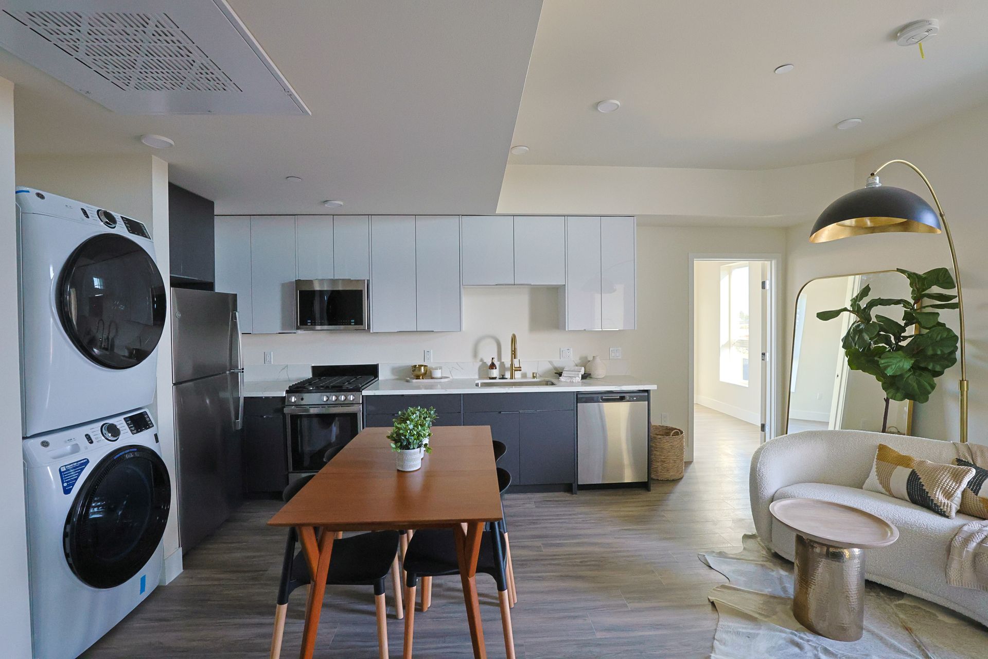 A kitchen with a table and chairs and a washer and dryer stacked on top of each other.