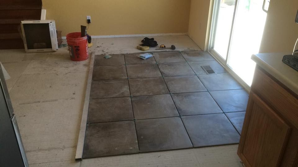 A tile floor is being installed in a kitchen