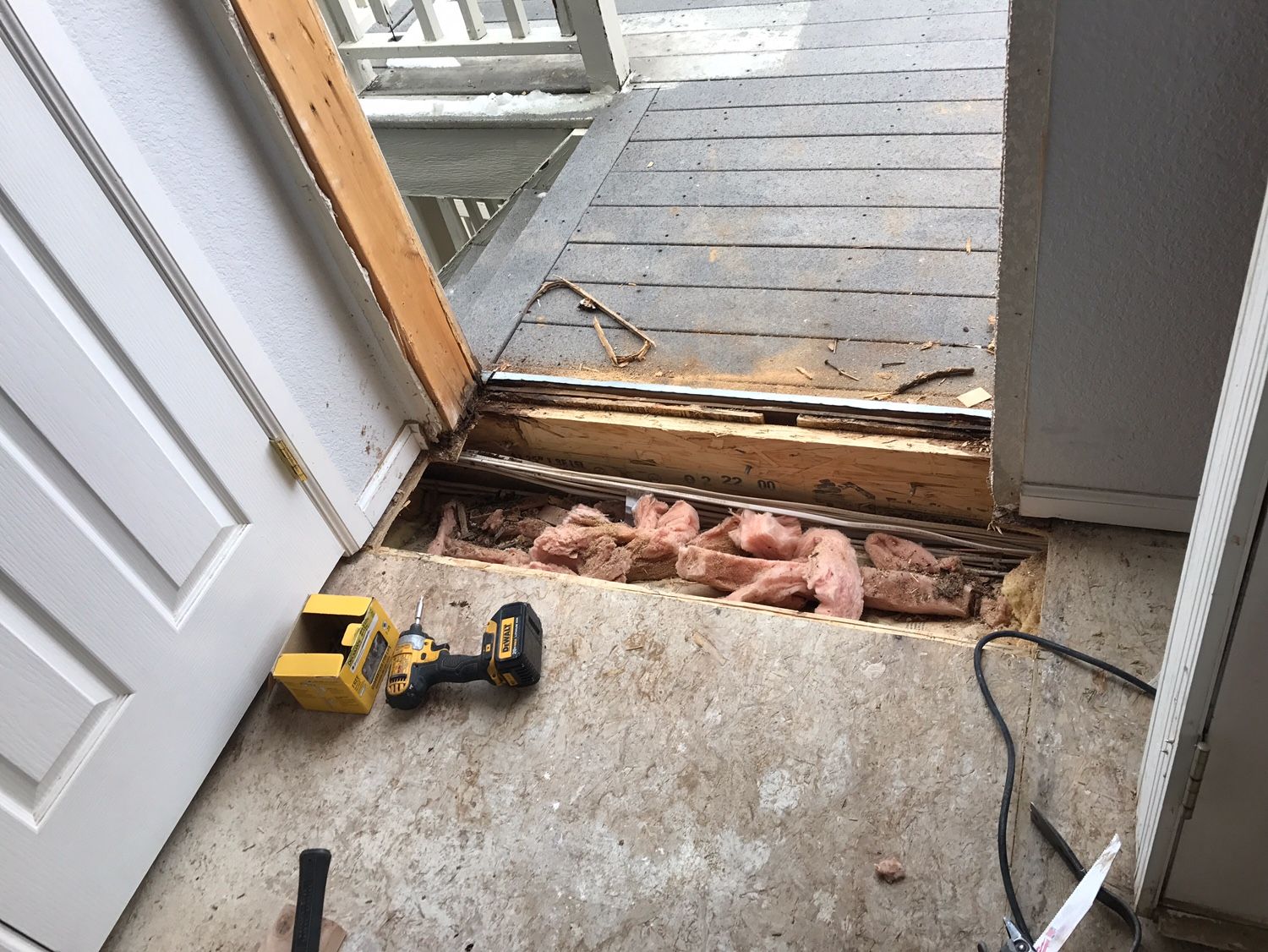 A drill is sitting on the floor next to a door.