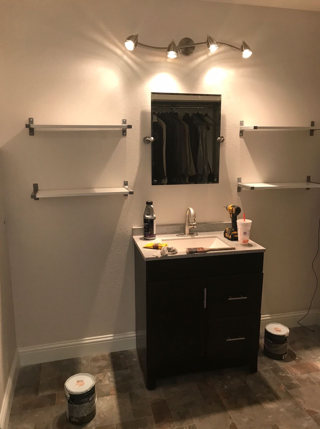 A bathroom with a sink , mirror , and shelves.