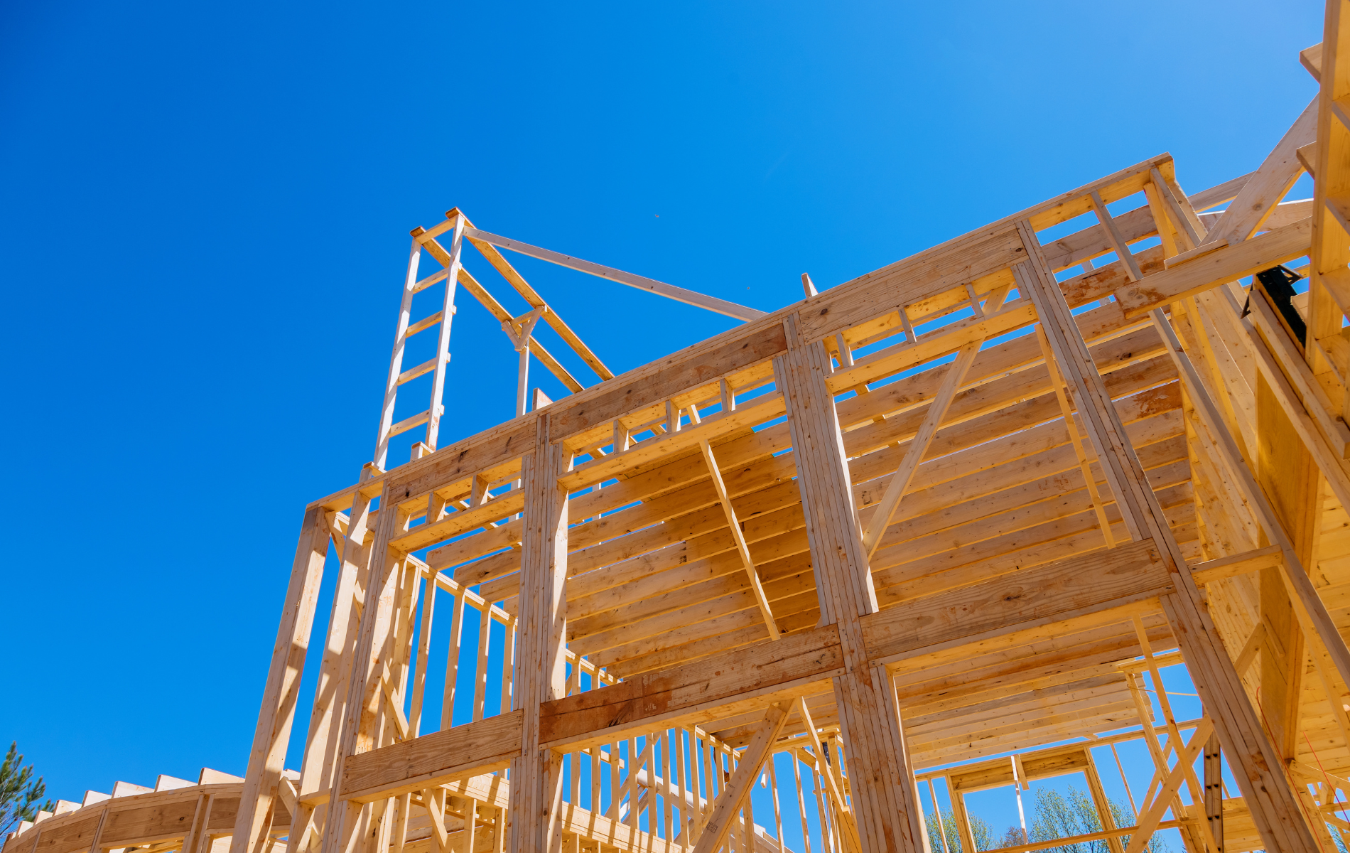 A wooden house is being built with a blue sky in the background.
