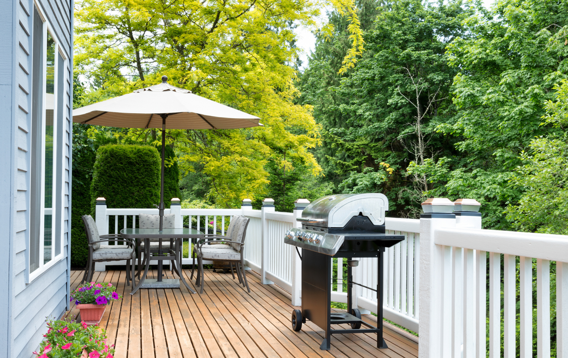 There is a grill on the deck with a table and chairs.