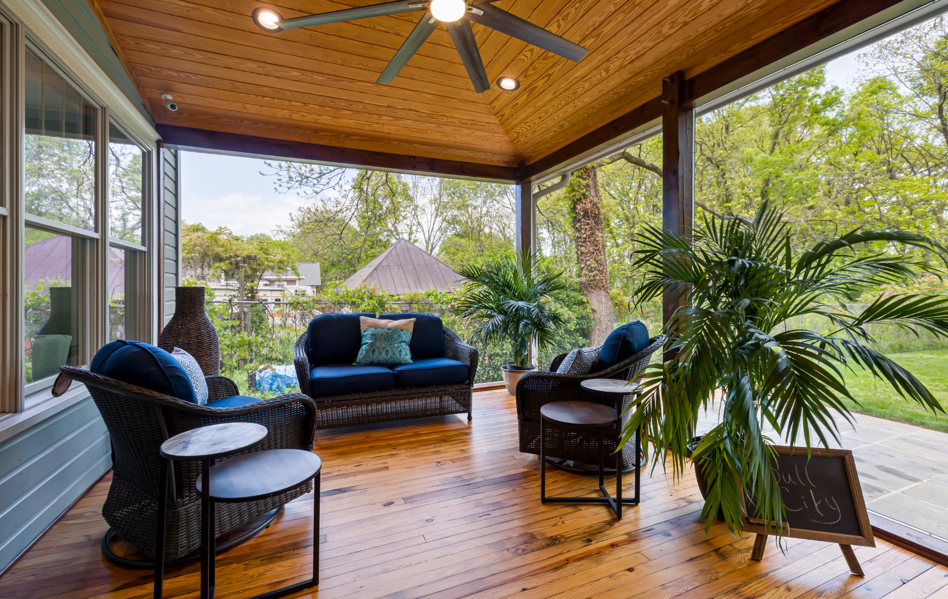 A screened in porch with furniture and a ceiling fan.