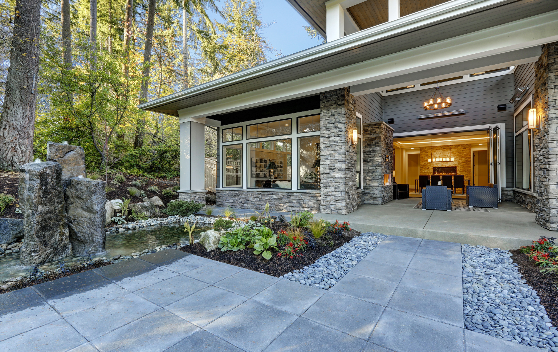 A large house with a patio and a pond in front of it.
