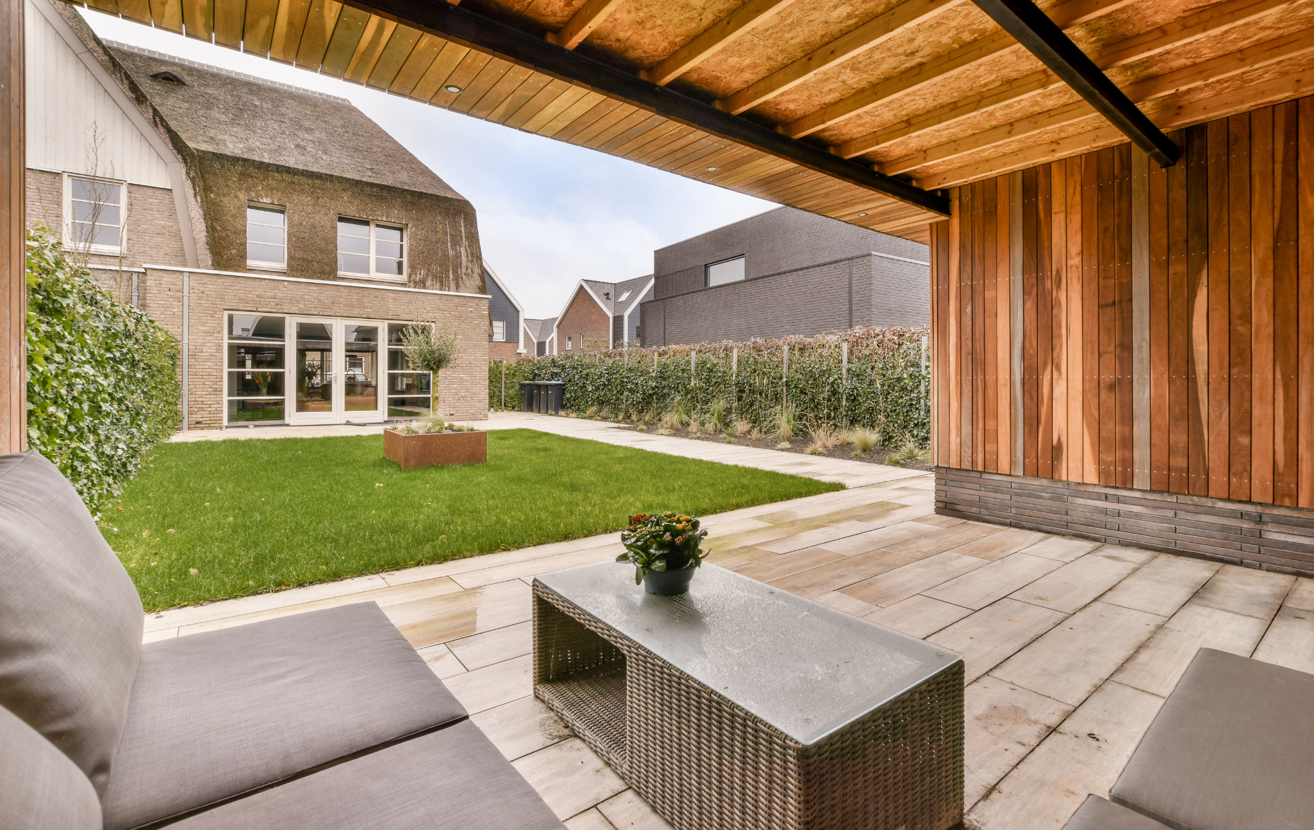 A patio with a couch and a table in front of a house.