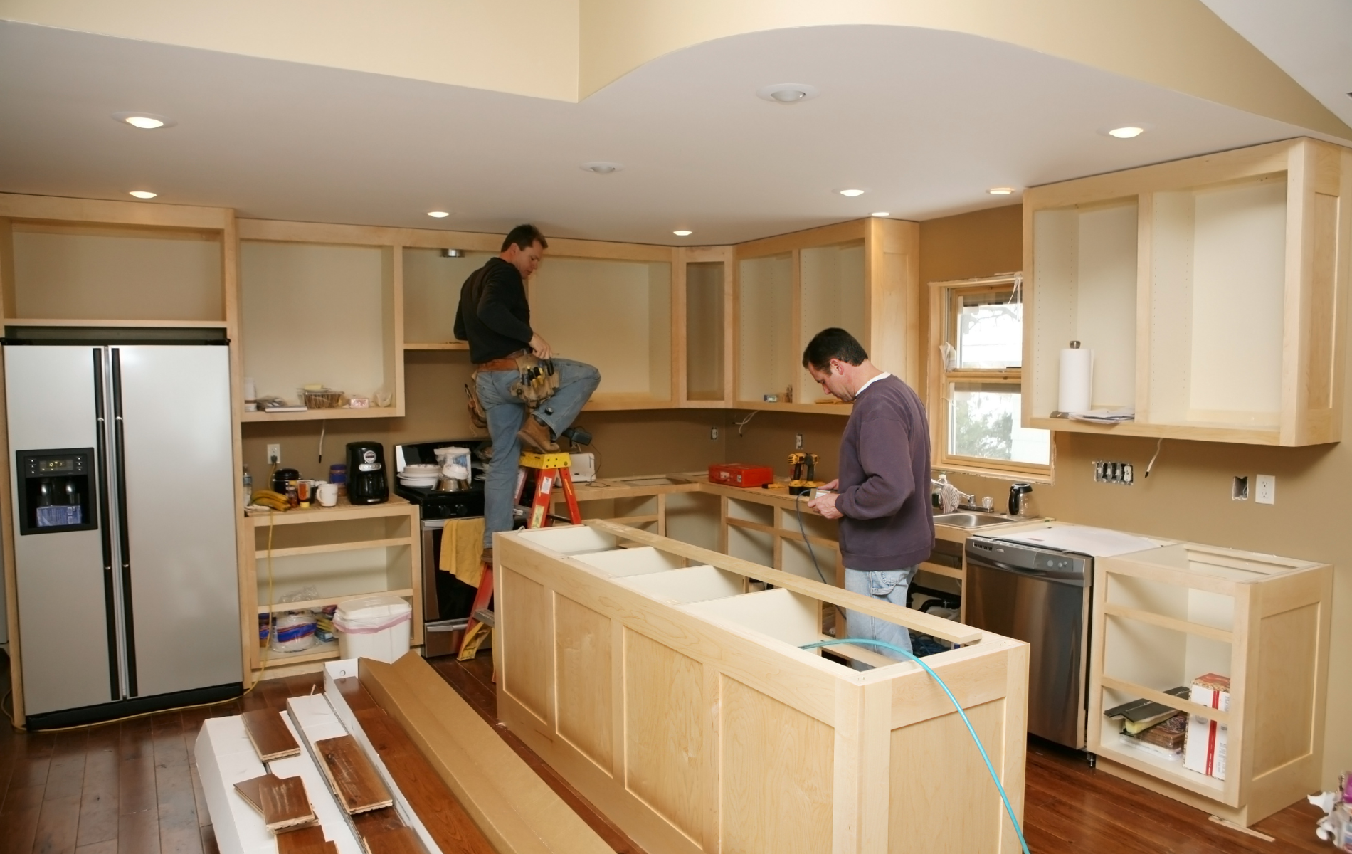 Two men are working on a kitchen in a house