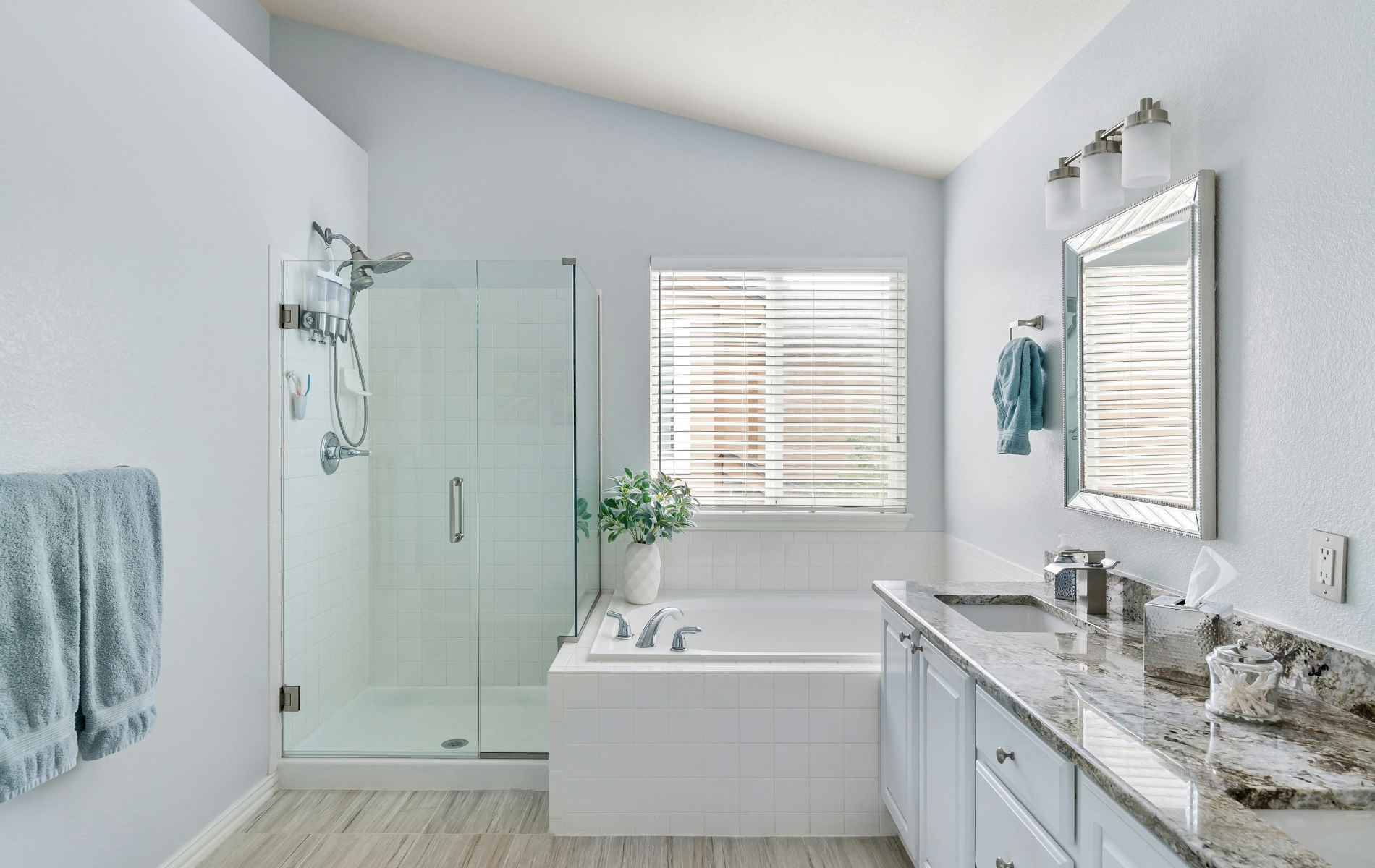 A bathroom with a tub , sink , mirror and shower.