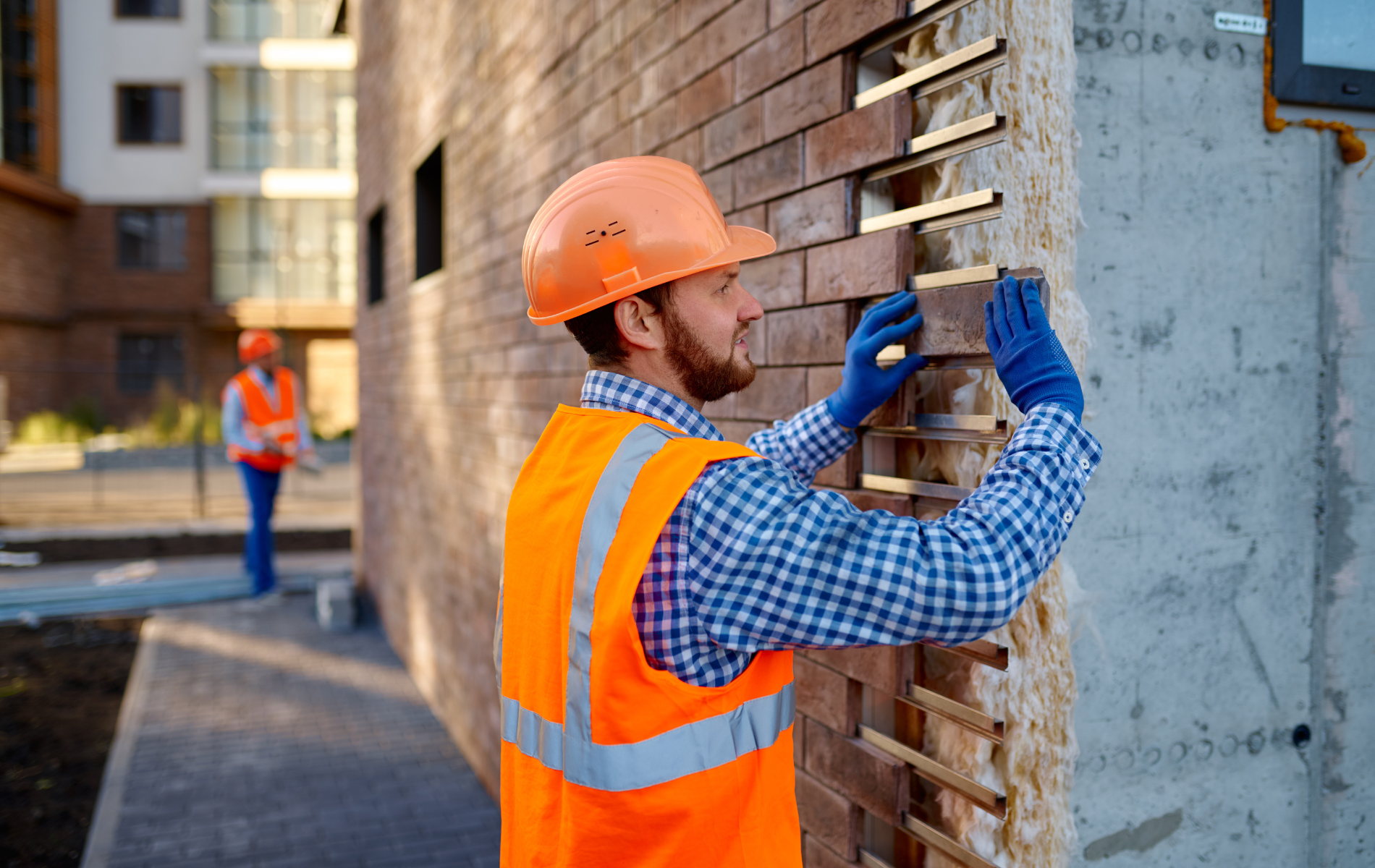 A construction worker is working on a brick wall.