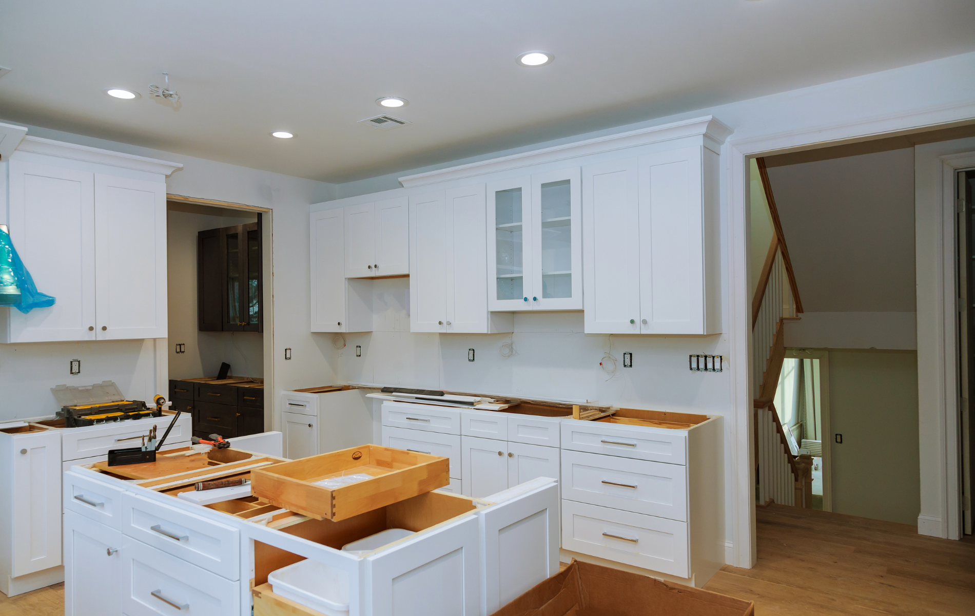 A kitchen under construction with white cabinets and wooden floors.