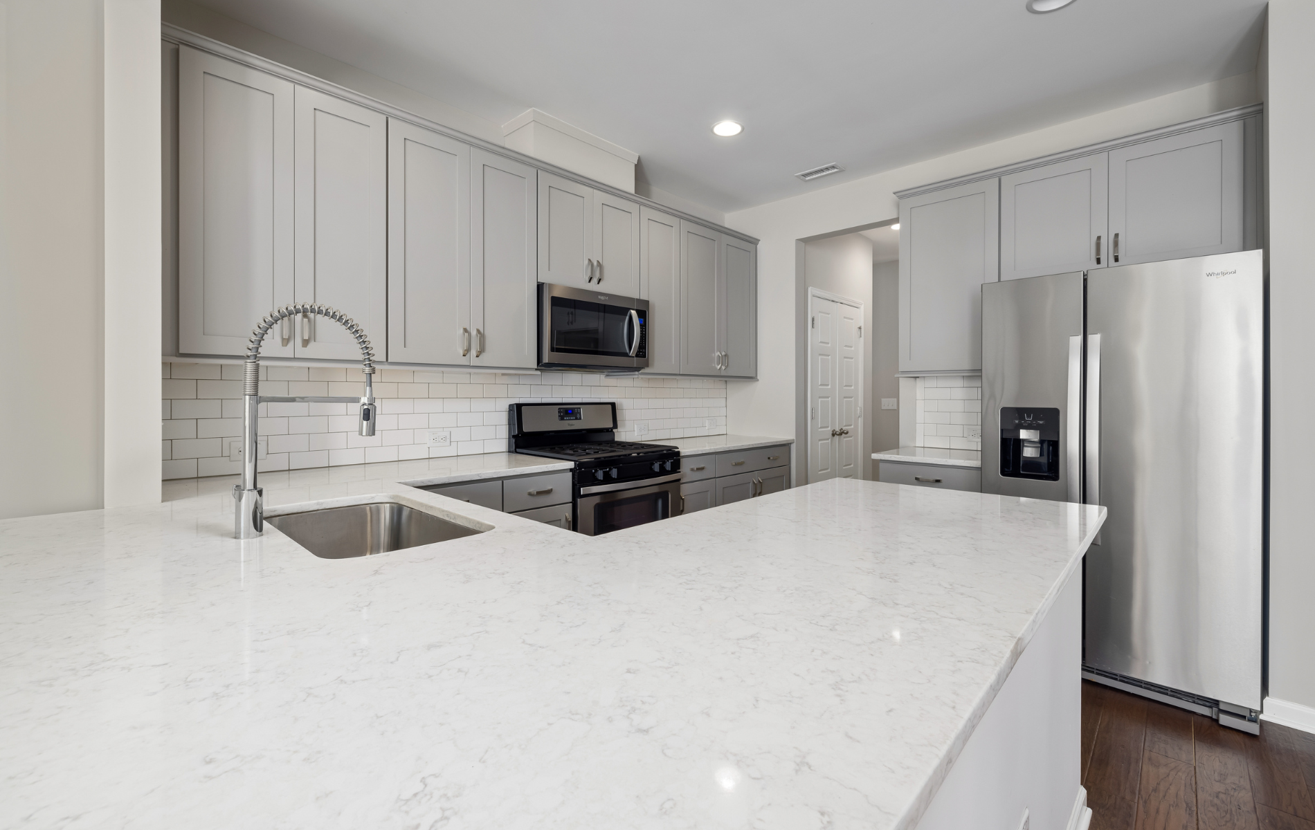 A kitchen with white cabinets , stainless steel appliances , a sink , and a refrigerator.