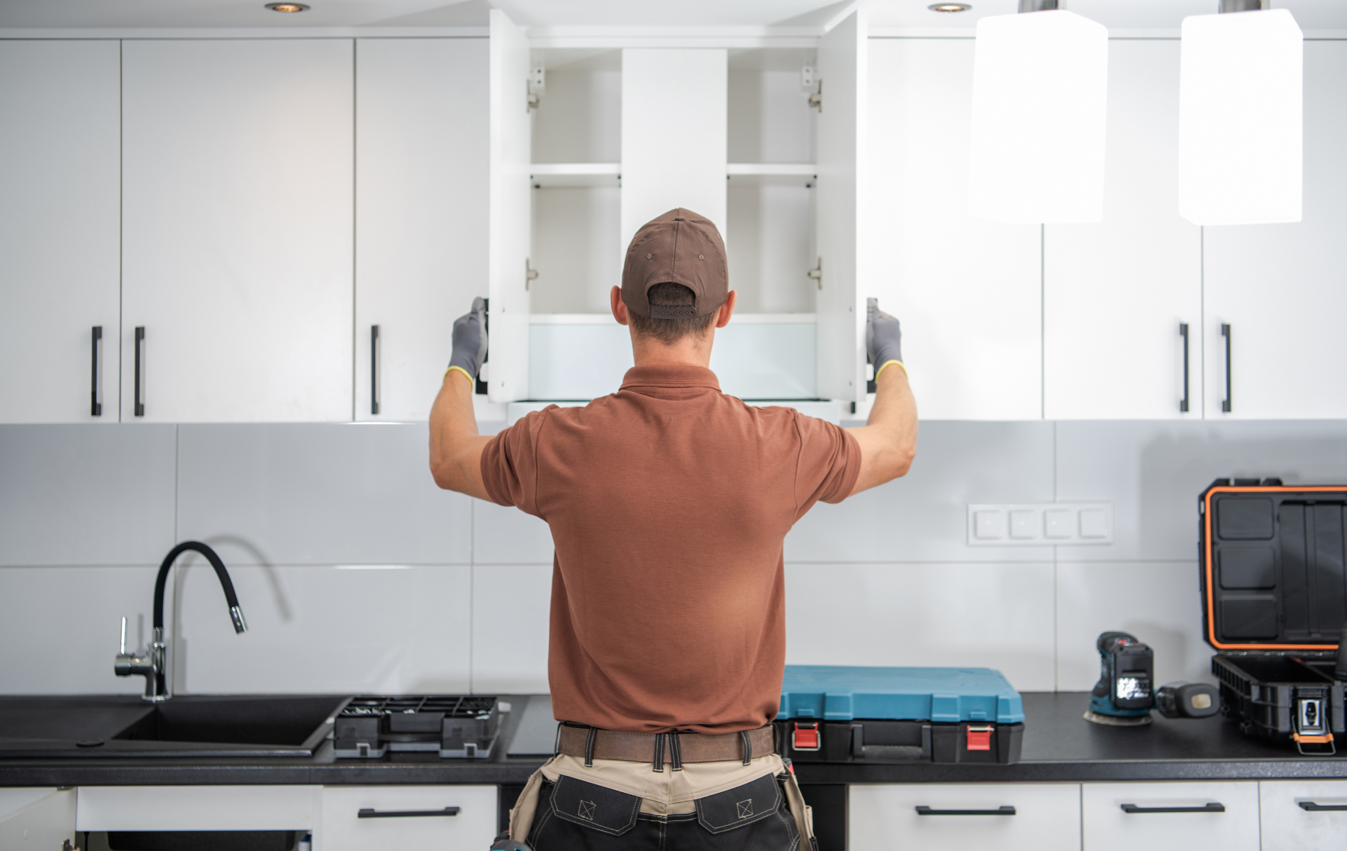 A man is installing cabinets in a kitchen.