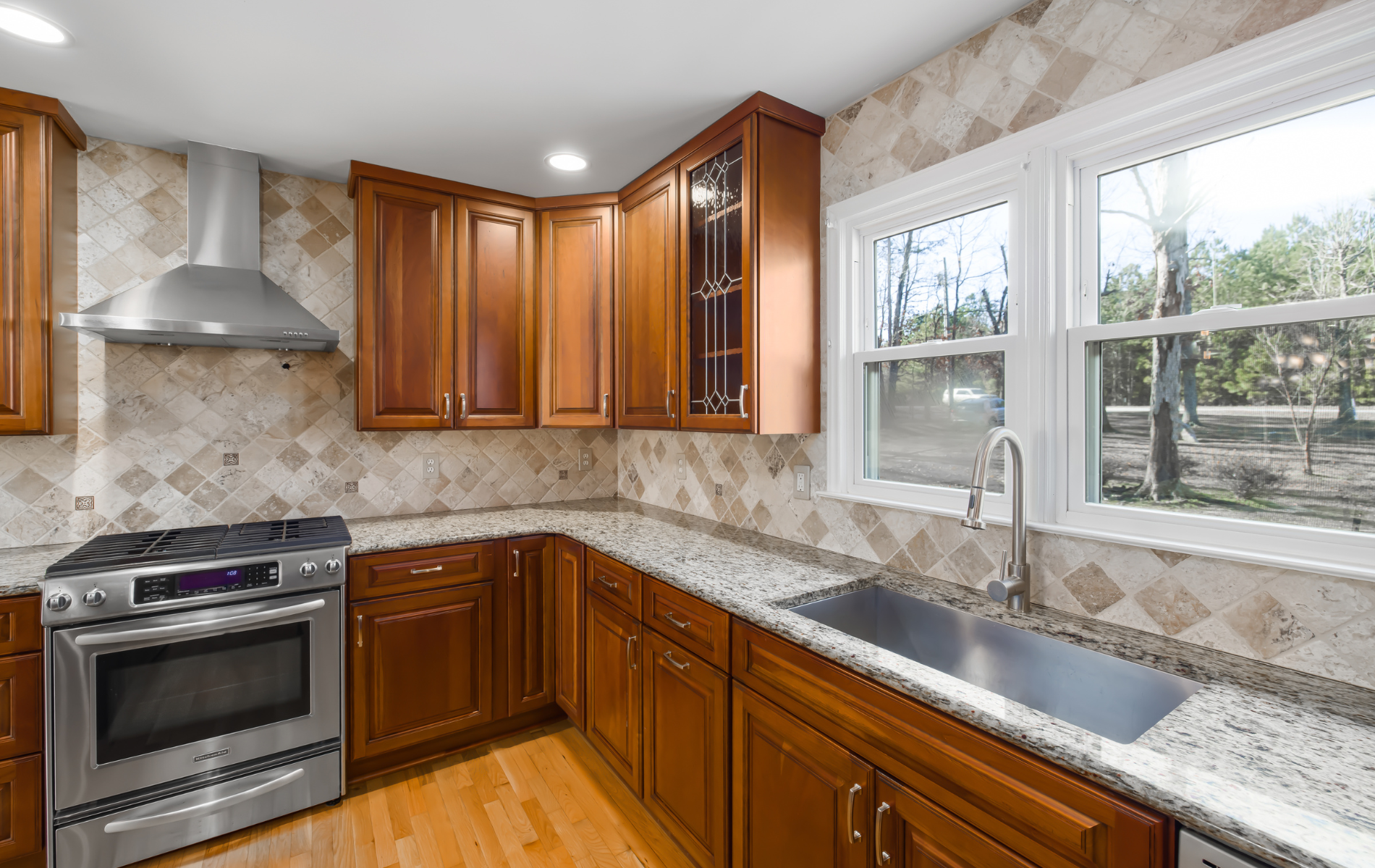A kitchen with stainless steel appliances , granite counter tops , and wooden cabinets.
