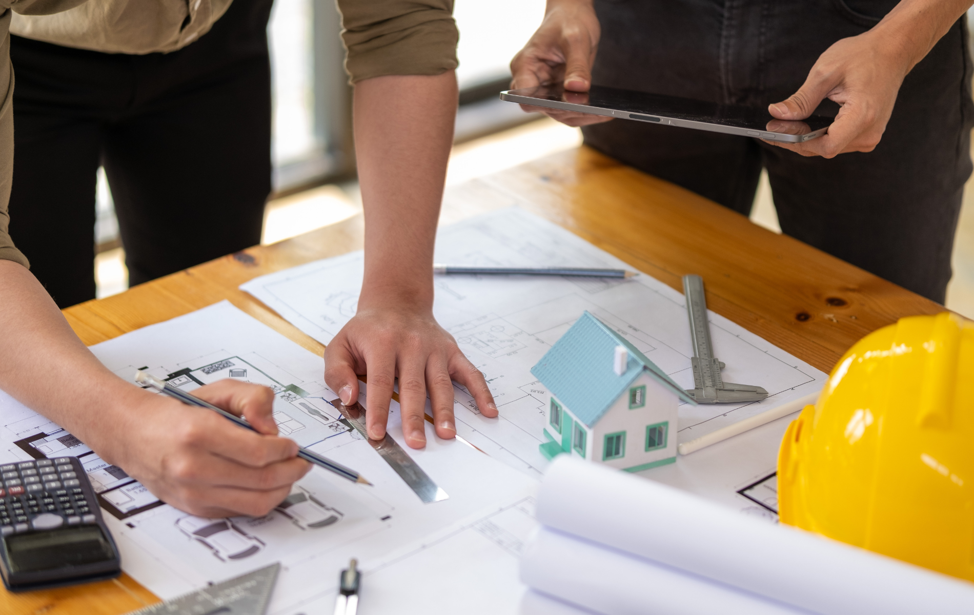 A couple of people are sitting at a table looking at a blueprint of a house.