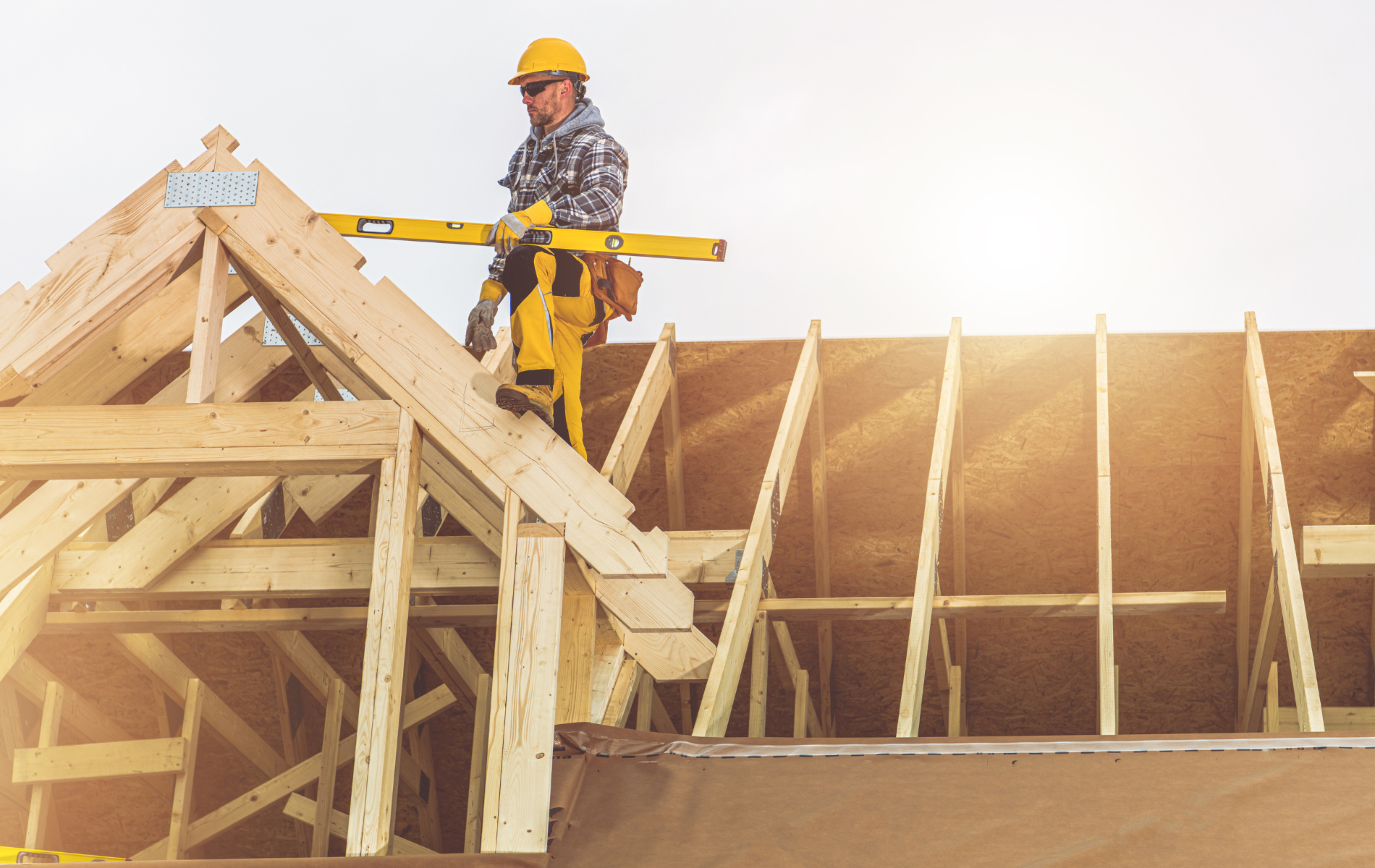 A construction worker is standing on top of a wooden structure.