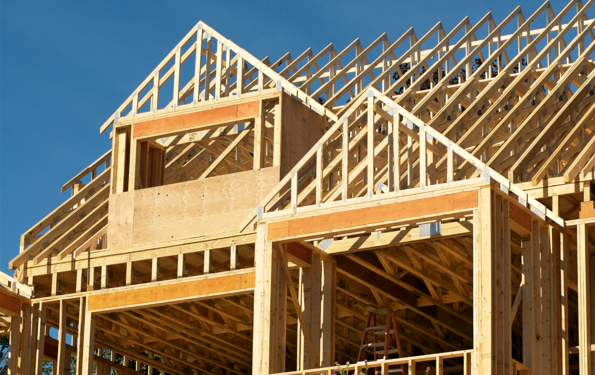 A large wooden house is being built with a blue sky in the background.