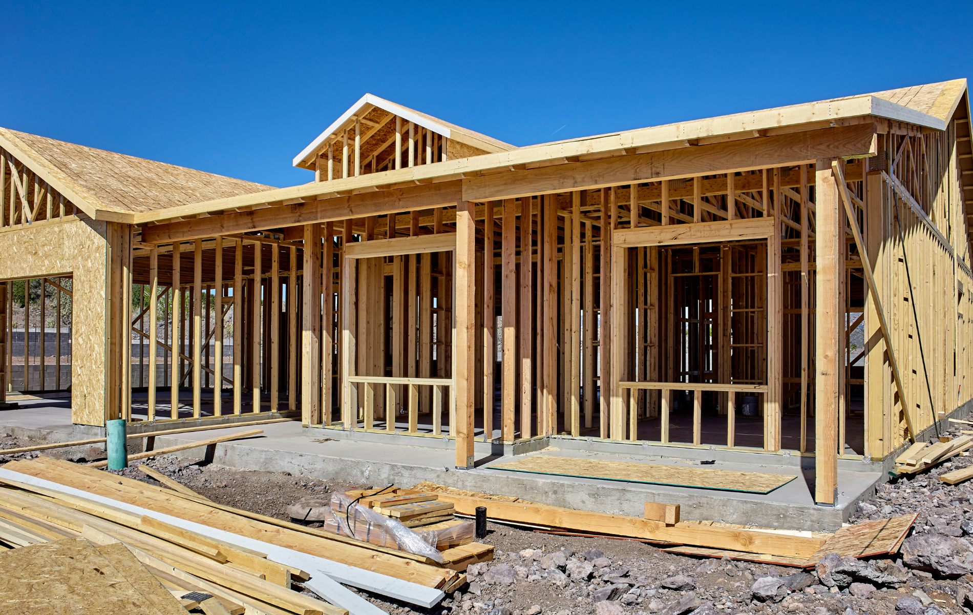 A house is being built with wooden beams and a blue sky in the background.