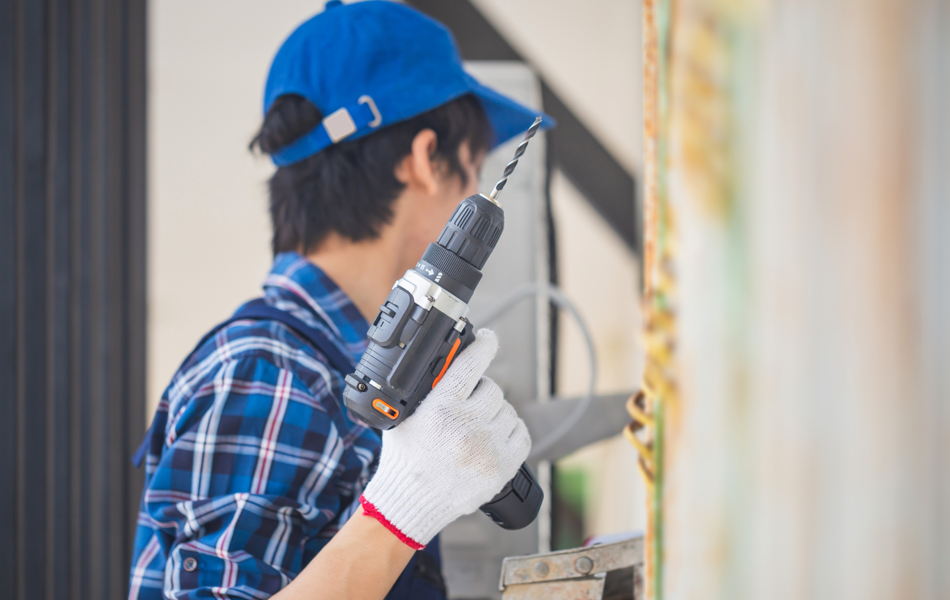 A man is using a drill on a wall.