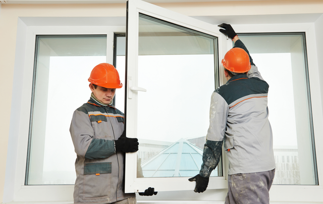 Two men are installing a window in a house.