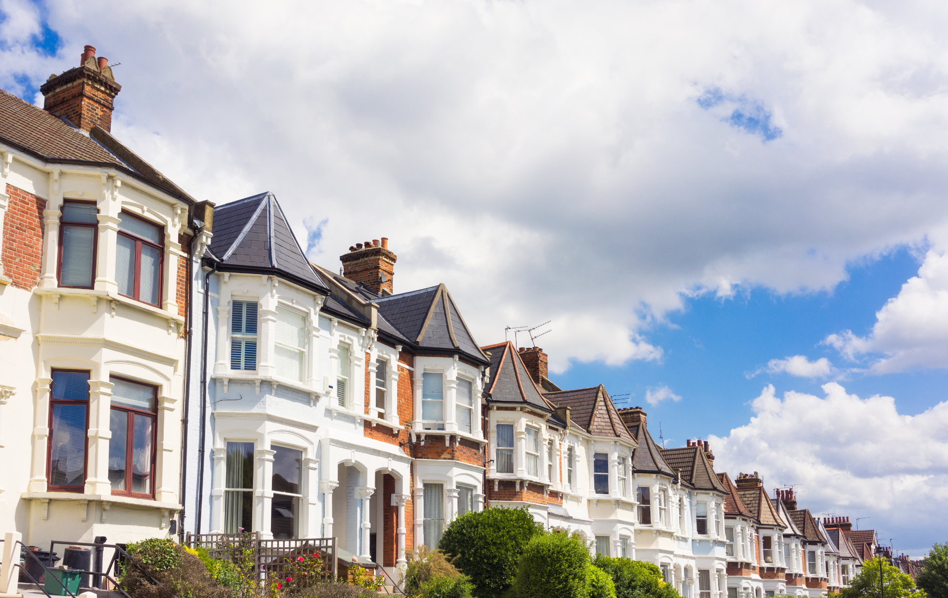 A row of houses on a sunny day with a blue sky in the background.