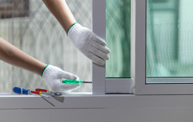 A person is fixing a window with a screwdriver.