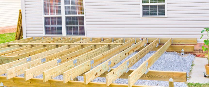 A wooden deck is being built in front of a house.