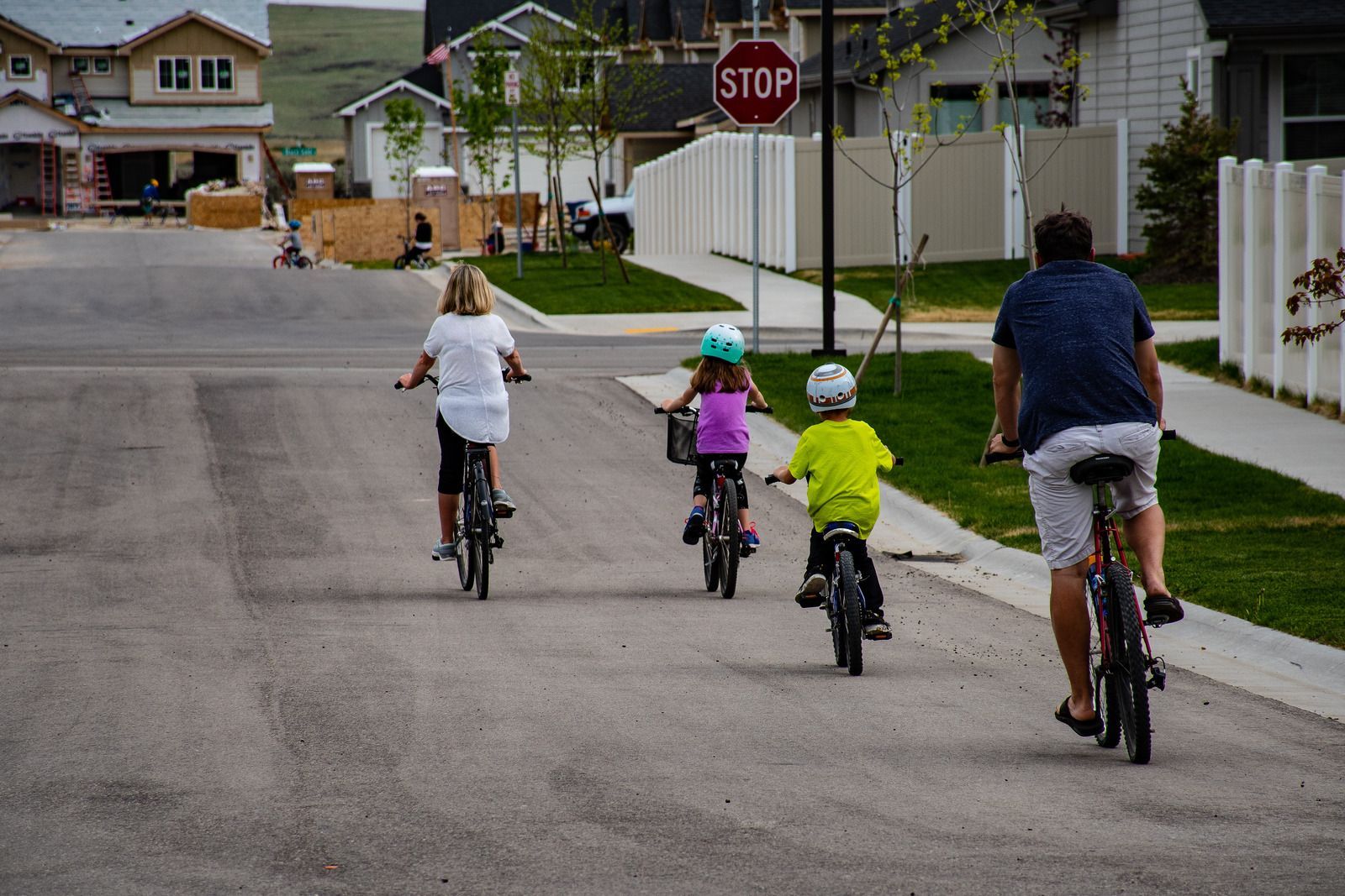 A group of people are riding bicycles down a street in front of a stop sign.