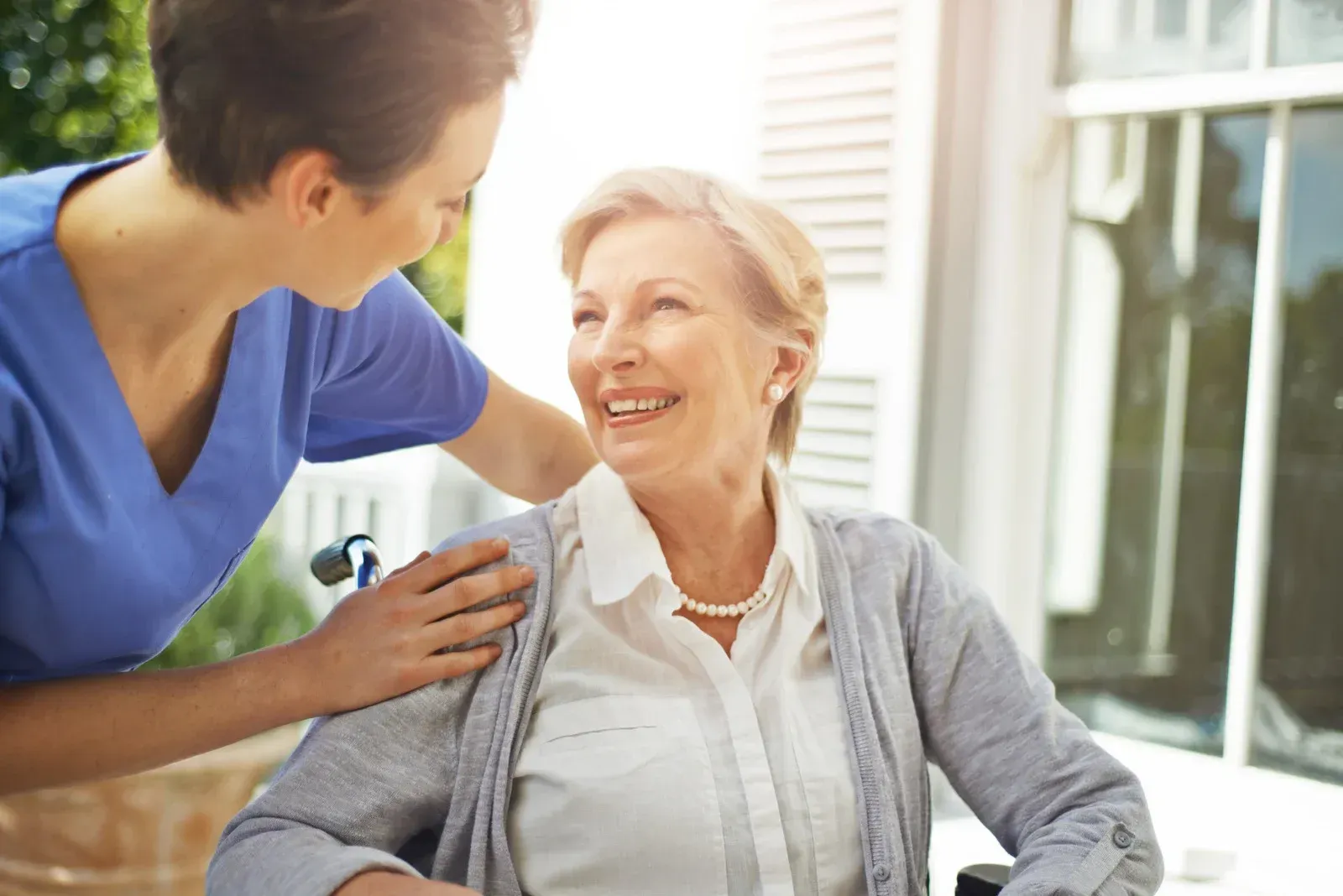 A nurse is talking to an elderly woman in a wheelchair.