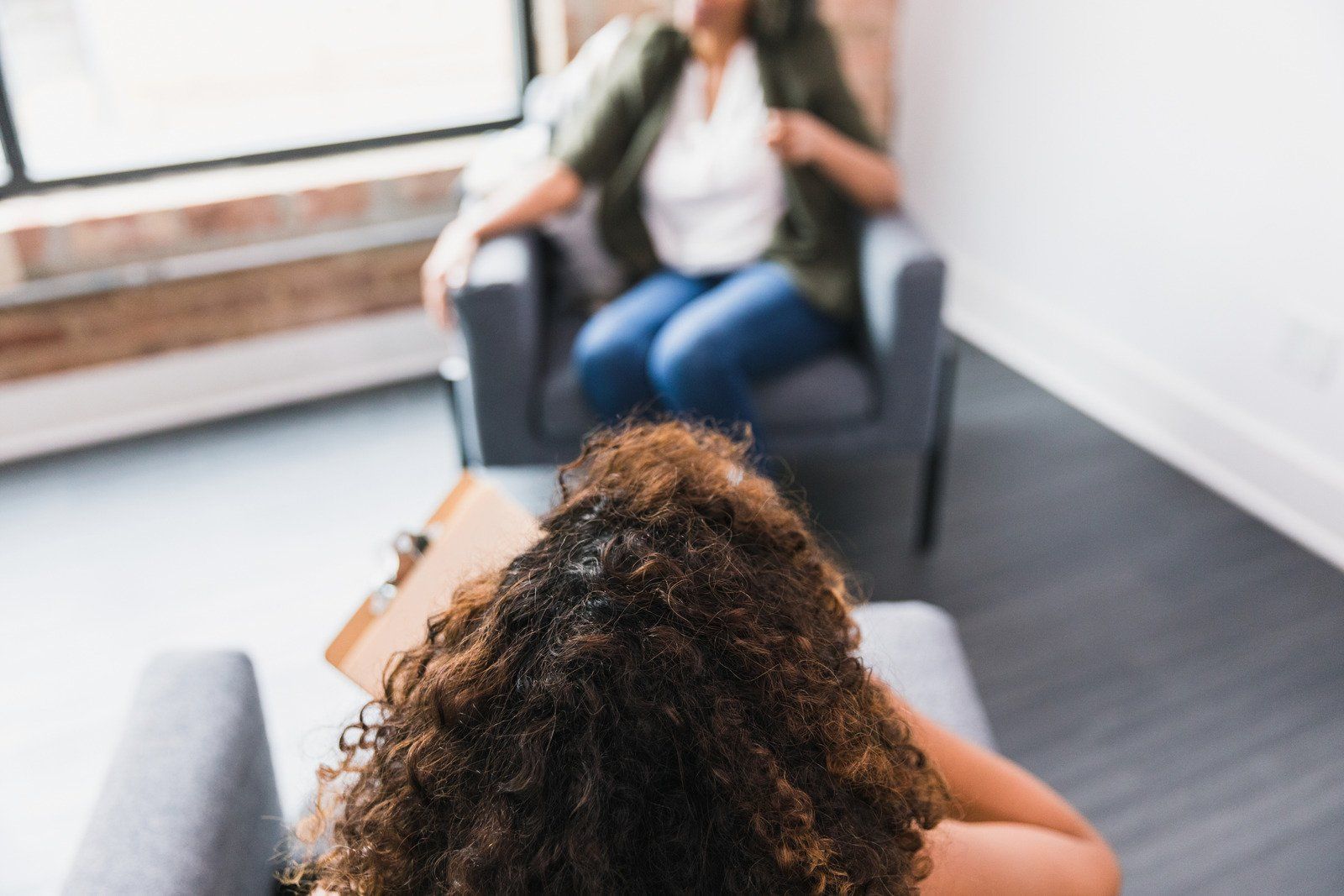 A woman is sitting in a chair talking to another woman.