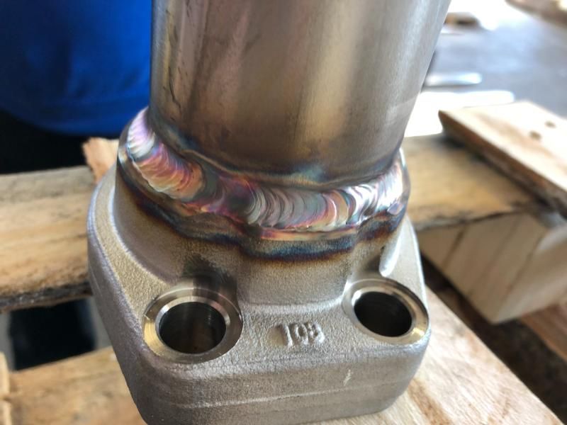 Un primo piano di un tubo di acciaio inossidabile posto sopra un pallet di legno.