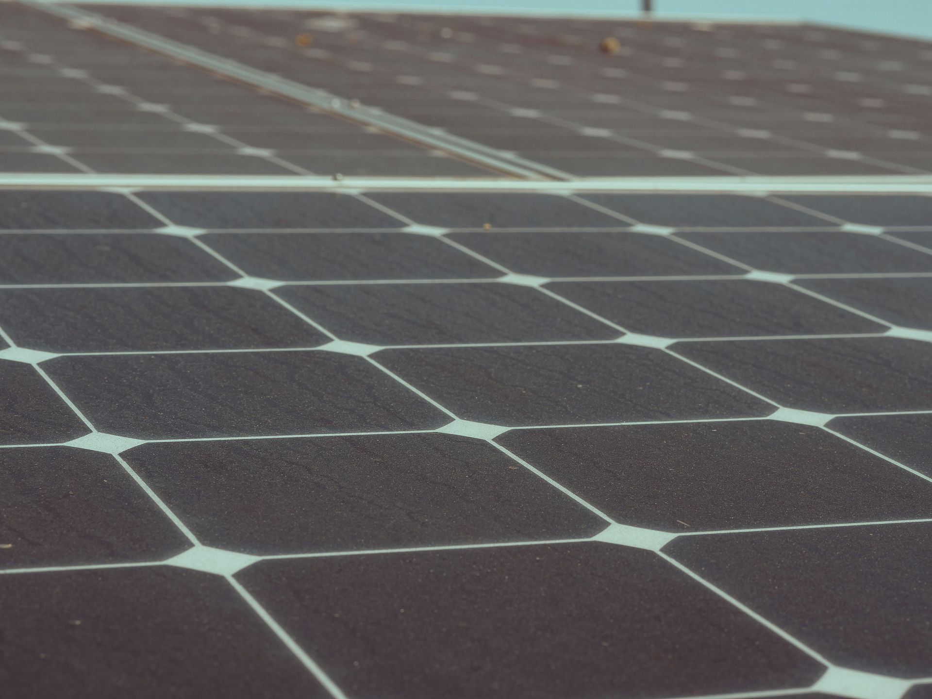 Close-up view of solar panels, dark squares with connecting lines, angled, outdoors.
