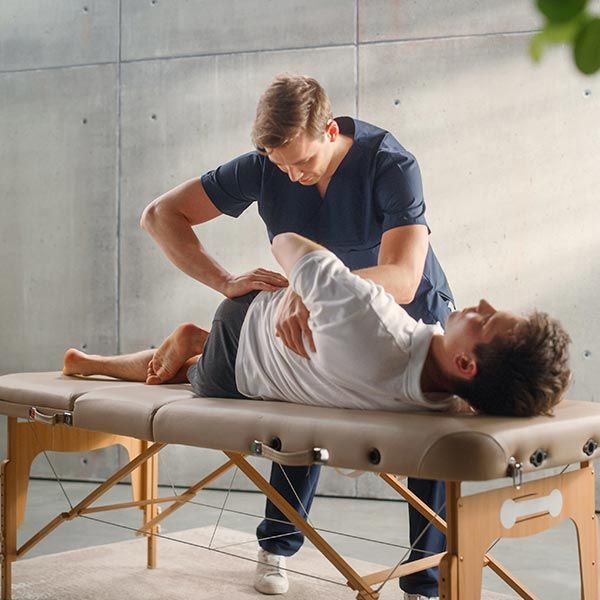 A physiotherapist works with a patient on specific muscle groups to recover from surgery.
