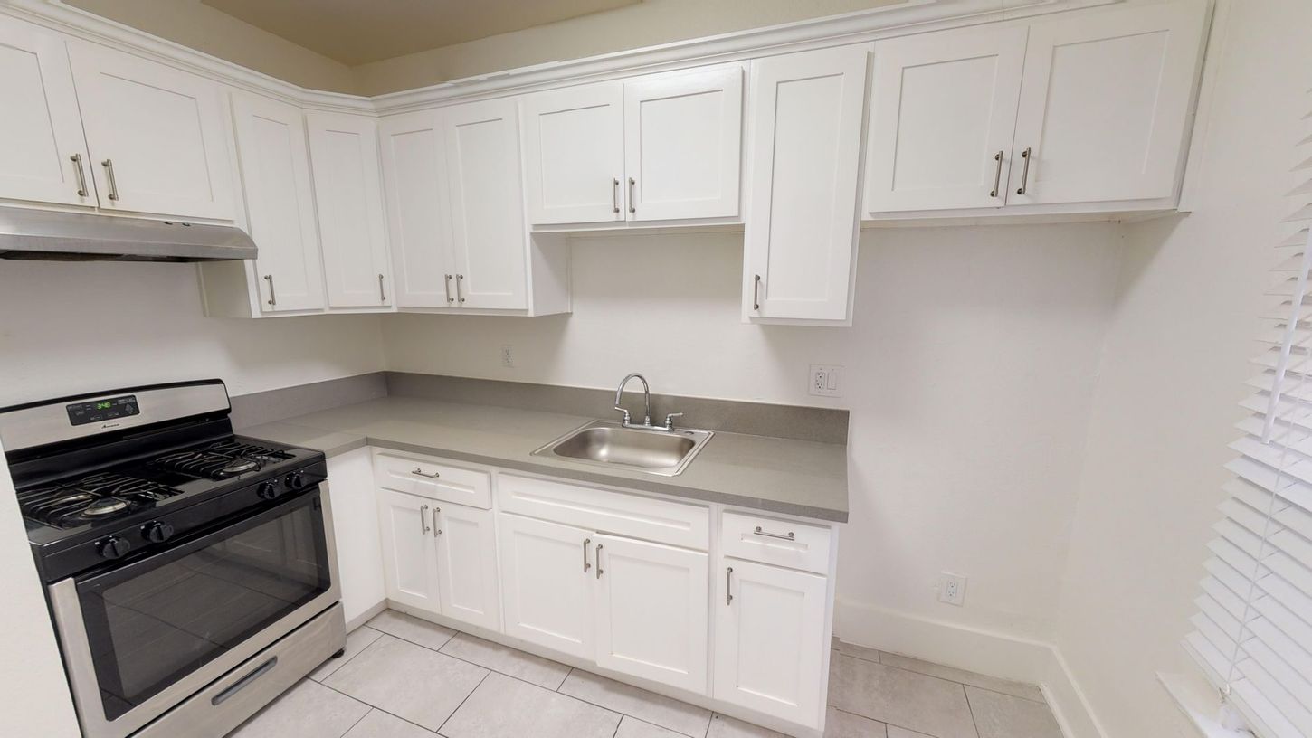 White kitchen with stainless steel appliances and light countertops.
