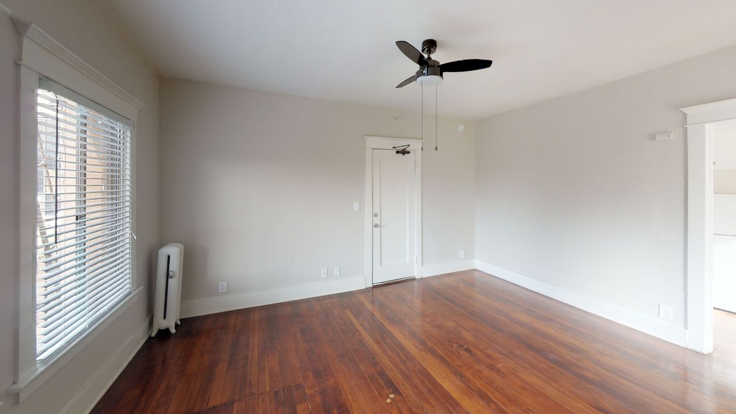Empty room with hardwood floors, a closed door, and a window with blinds.